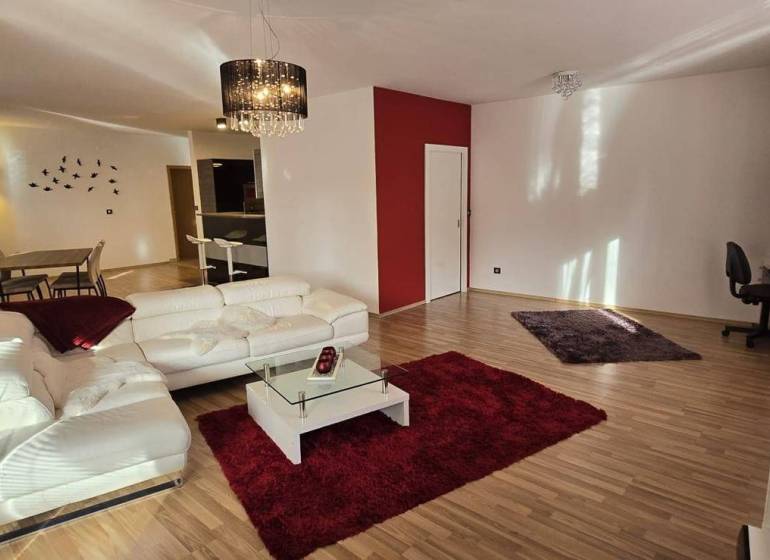 A spacious living room with a white sofa and a red carpet in a 3-room apartment.