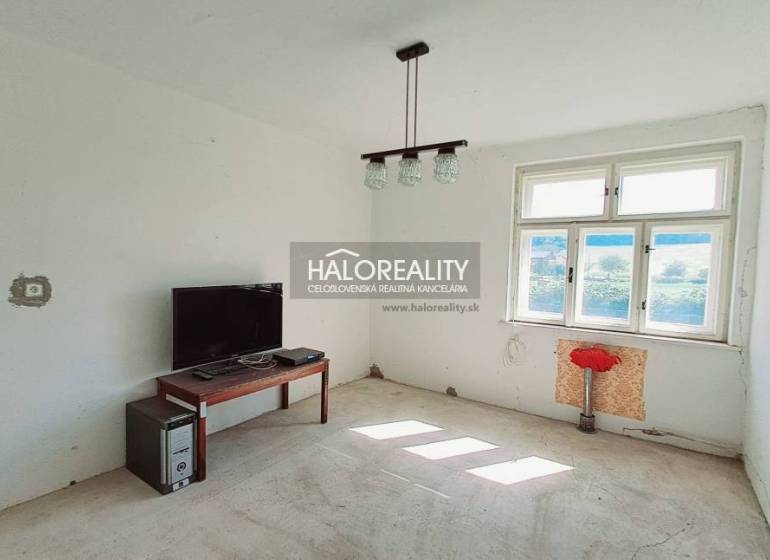 A room in a family house with a window, a table, a television, and a computer.
