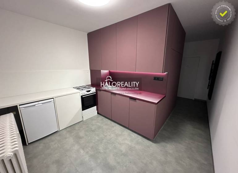 A hallway with coat racks and a mirror in a one-room apartment, light flooring and white walls.