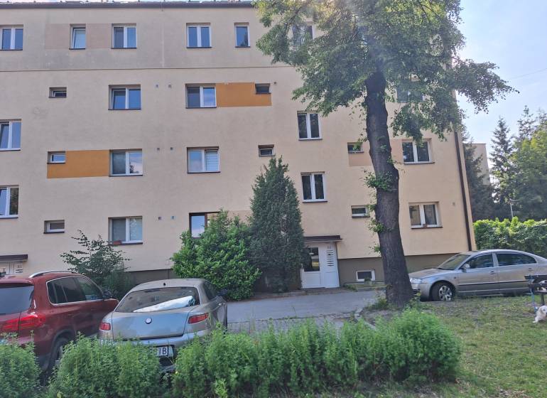 Apartment building in Prešov with parked cars and trees in front of a 4-room apartment.