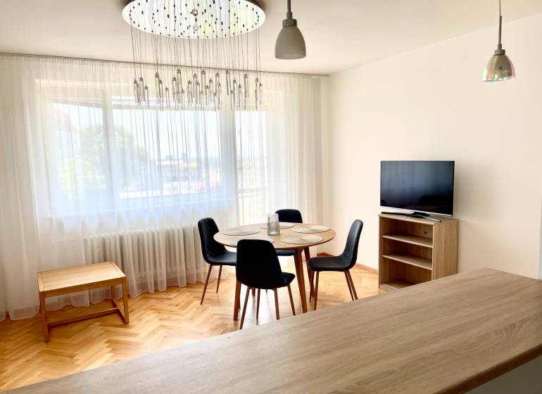 2-bedroom apartment with wooden flooring, dining table, TV, and modern lighting.