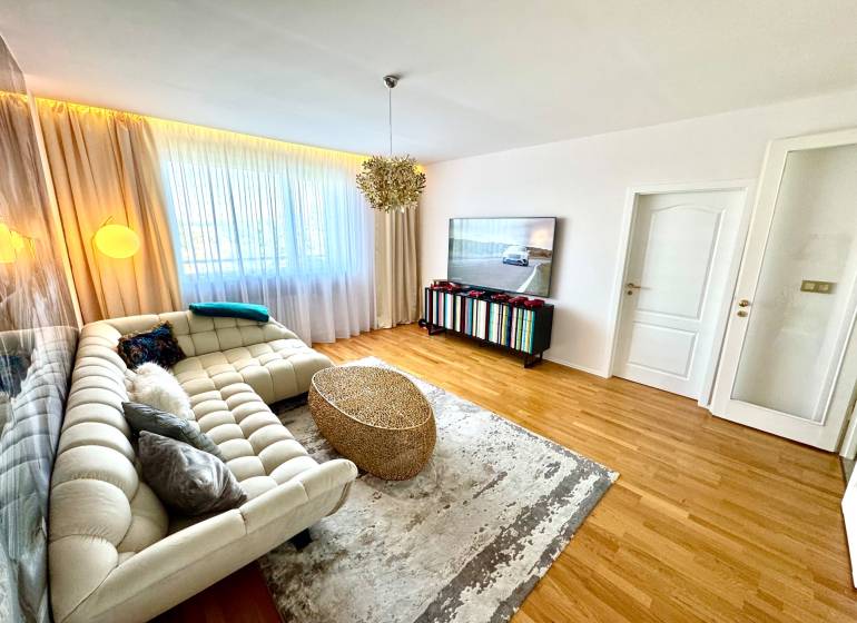 Living room in a 3-room apartment with a sofa, television, and curtains on the window.