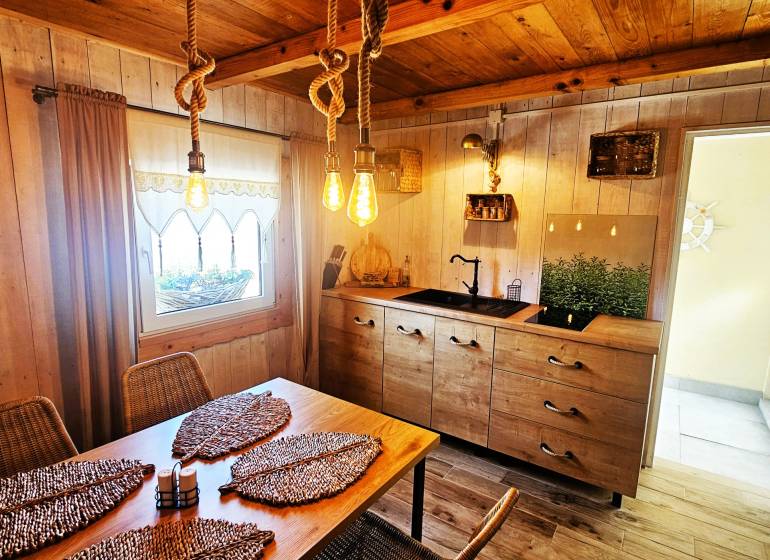 Interior of a cottage with wooden furniture, kitchen unit, and decorative elements.