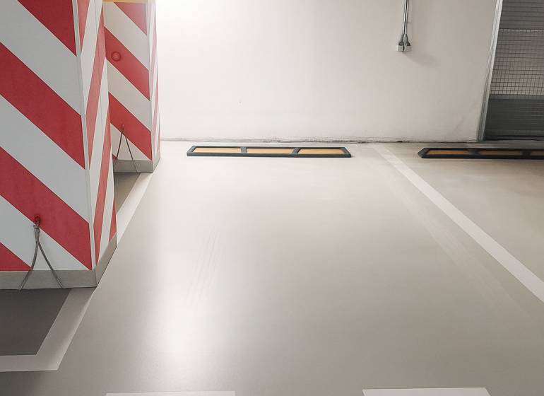 A parking space in garages with warning stripes on the walls and ventilation.