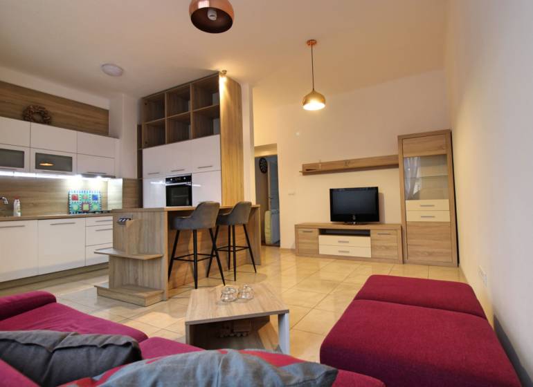 Living room with kitchen and dining area in a 3-room apartment with a purple sofa.