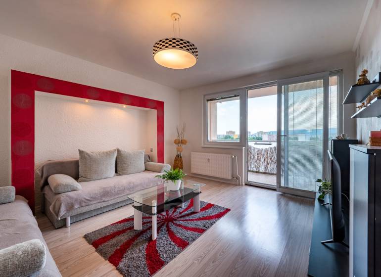 Living room in a 3-room apartment with a sofa, balcony, and television.