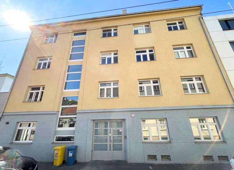 Building on Cintorínska Street in Bratislava – Old Town with parking and waste containers.
