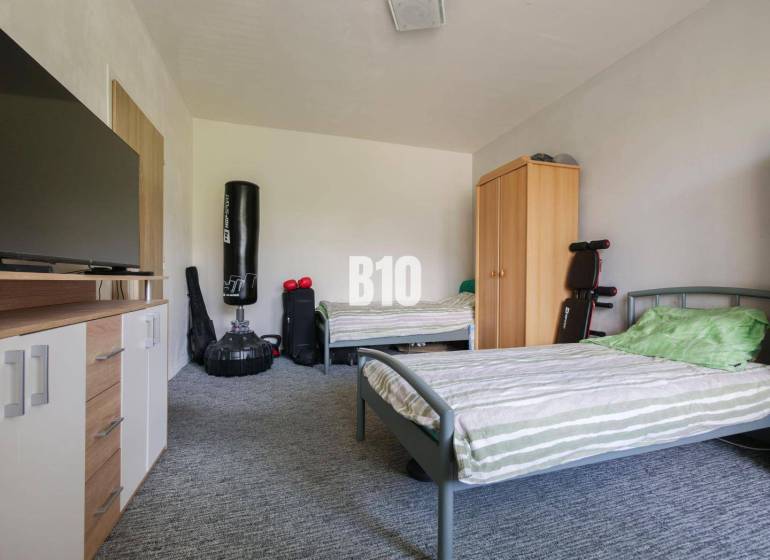 Two beds, a cabinet, a television, and a punching bag in a studio apartment.