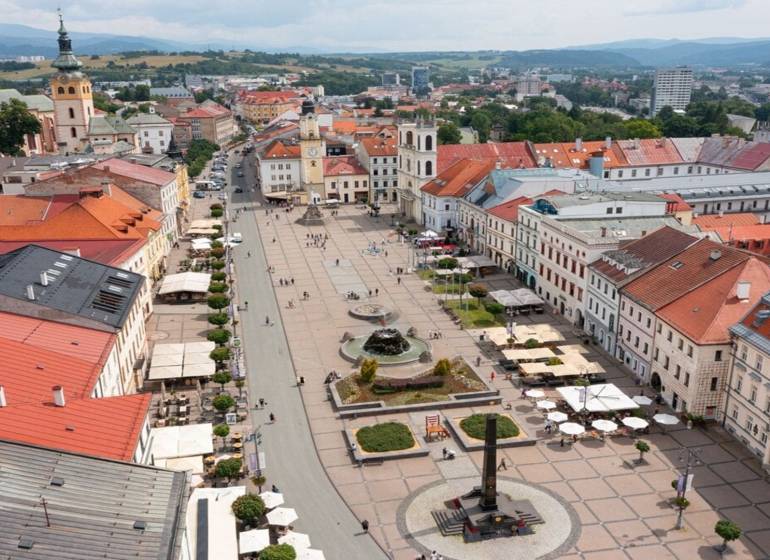 In the picture, there is a square in Banská Bystrica with an advertisement for a 1-room apartment.