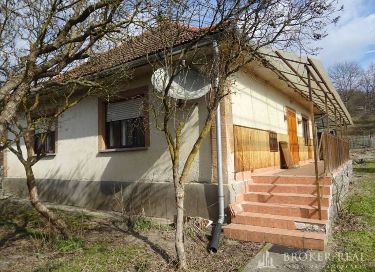 A family house in Füzérkomlós with a front garden, terrace, staircase, and wooden cladding.