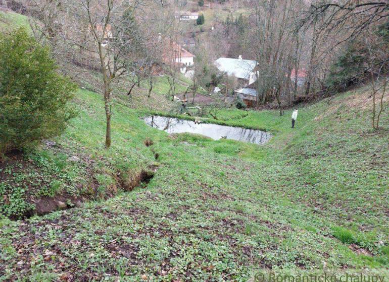 A peaceful view of gardens in Banská Bystrica with trees and a pond.