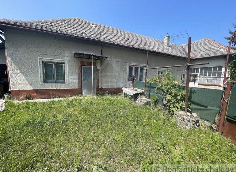 The back part of a family house in Nové Zámky with a grassy yard and older equipment.