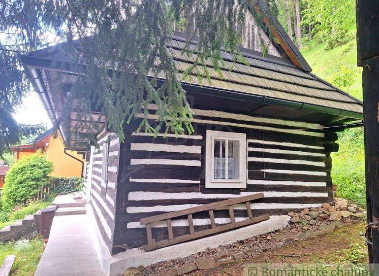 A wooden family house in the forest near Ružomberok, surrounded by greenery and with a shingle roof.