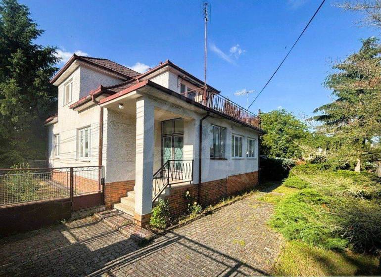 A family house in Plavecký Štvrtok with a white facade and a large garden in summer weather.