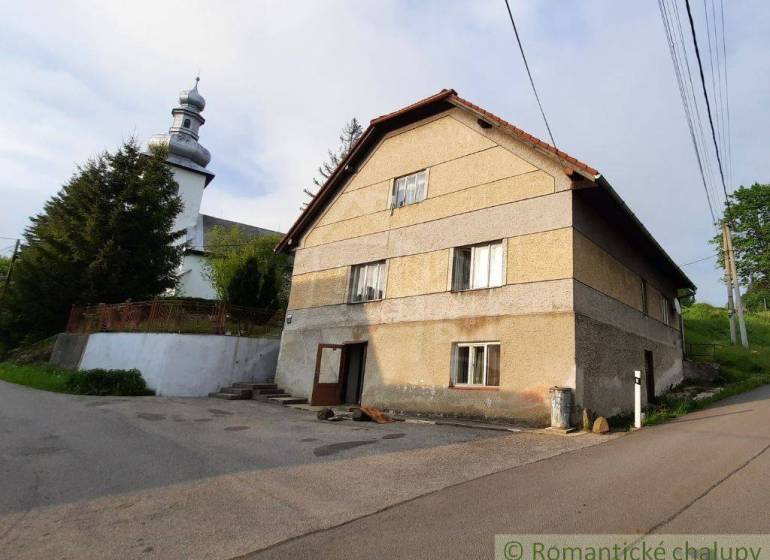 A family house near the church in Žiar nad Hronom with a large tree and power lines.
