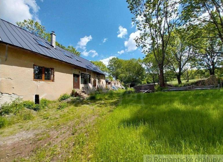 A cottage in Ábelová with a blue roof surrounded by greenery and trees.