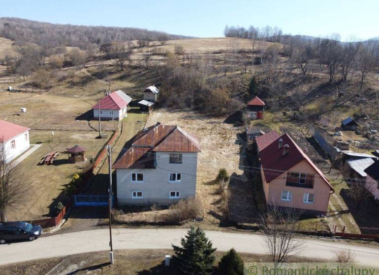 Family houses in Nová Sedlica surrounded by hills and fields with visible buildings and a road.