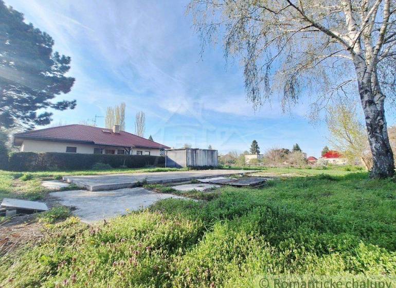 A grassy plot with a bungalow surrounded by trees, ideal for living in nature.