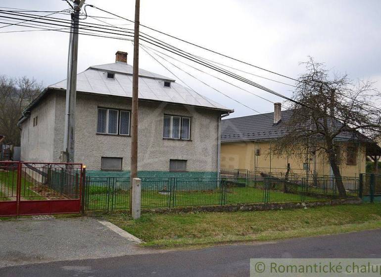 A family house with a metal roof, garden, fence; rural environment.