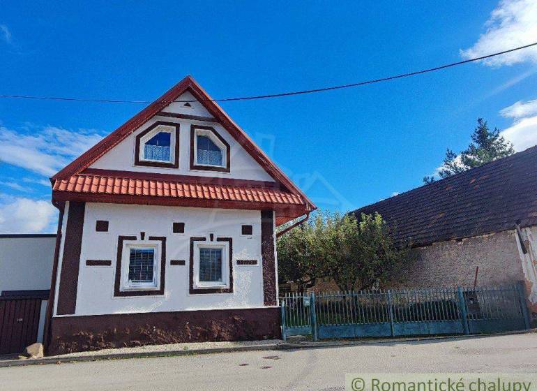 Traditional family house with a wooden roof and typical windows, street, fence, sky.