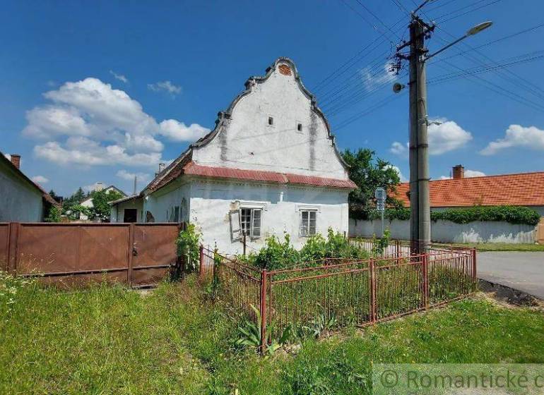 In the picture, there is a traditional family house with a front garden and a gate.