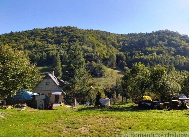 A family house in a quiet nature, surrounded by trees, with hilly landscape in the background.
