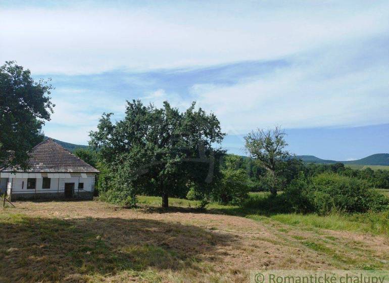 A wooden cabin visible in a picturesque landscape surrounded by trees and nature.