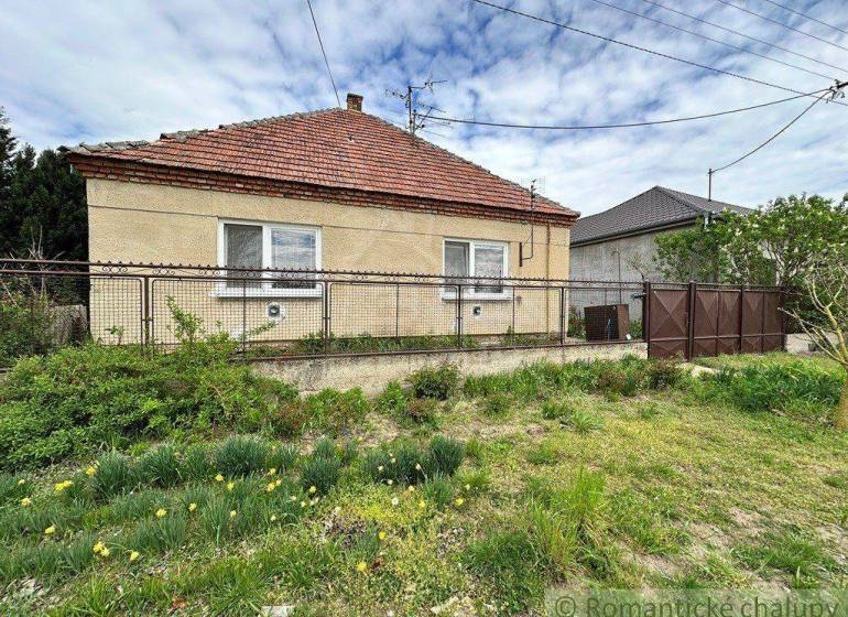 A family house with a fence and a garden, located in the countryside.