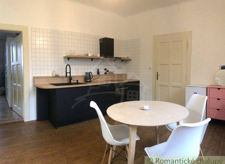 A kitchen in an apartment with wooden furniture and a table for a 2-room apartment for rent.