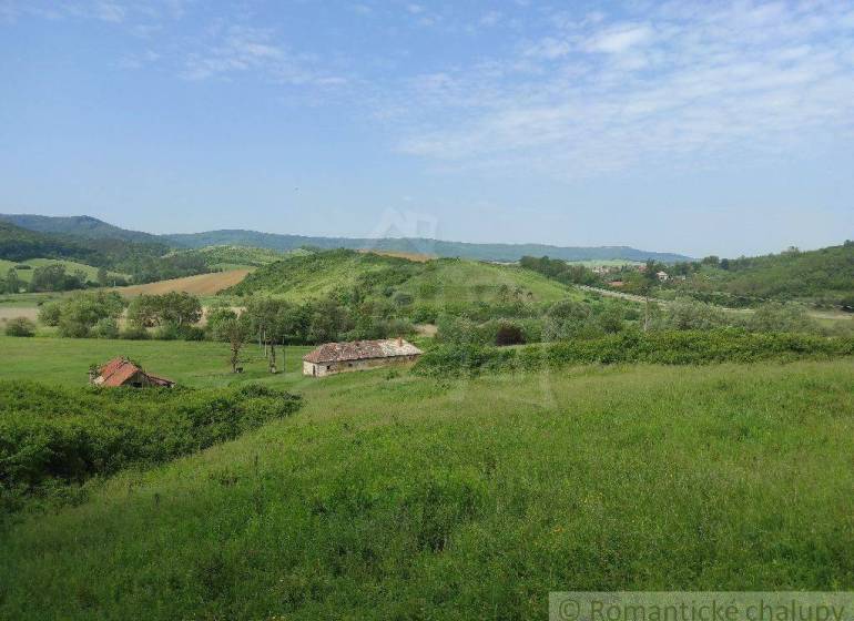 Hilly landscape with meadows and family houses, peaceful environment, nature, and yard.