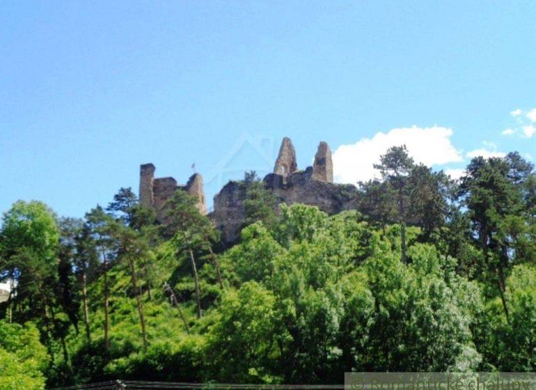 A ruin of a castle on a hill surrounded by trees, an ideal place for living and relaxation.