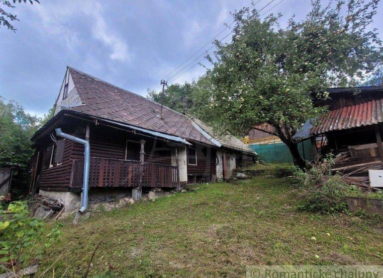 An old wooden family house with a gable roof and a fruit tree in the garden.