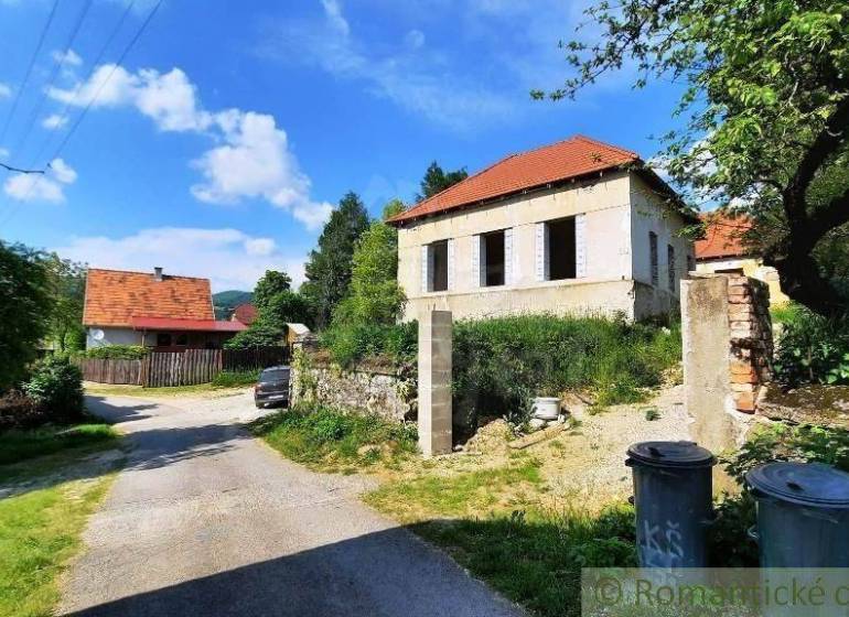 A nice family house for renovation, surrounded by trees, road, trash bins.