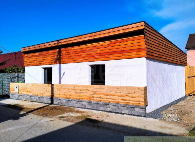 A family house with wooden cladding and a white facade on a quiet street.