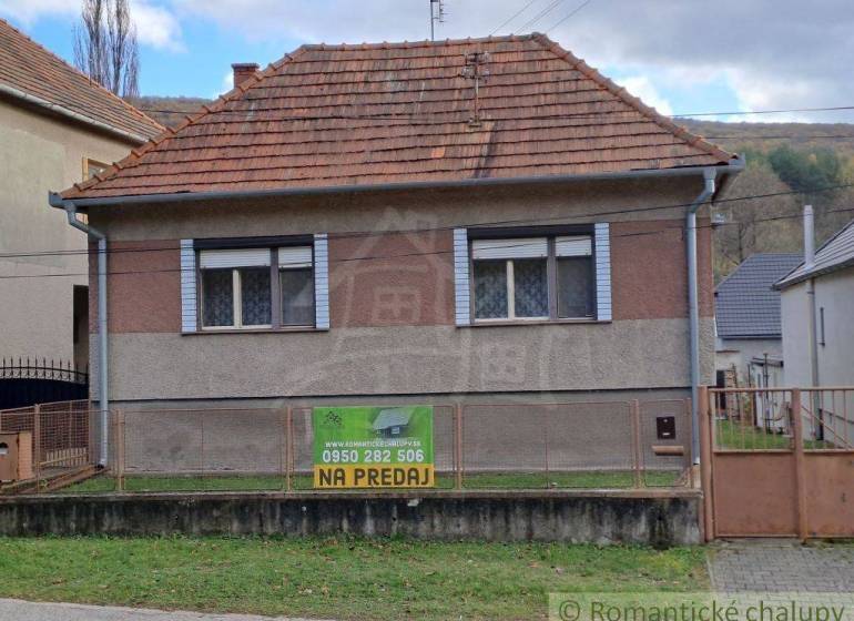Older family house with a red roof for sale in a quiet village setting.