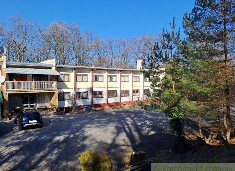 A residential building surrounded by trees and parking spaces, suitable for commercial premises.