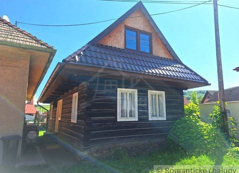 A traditional wooden house with windows and an attic in a sunny setting, a family home in the village.