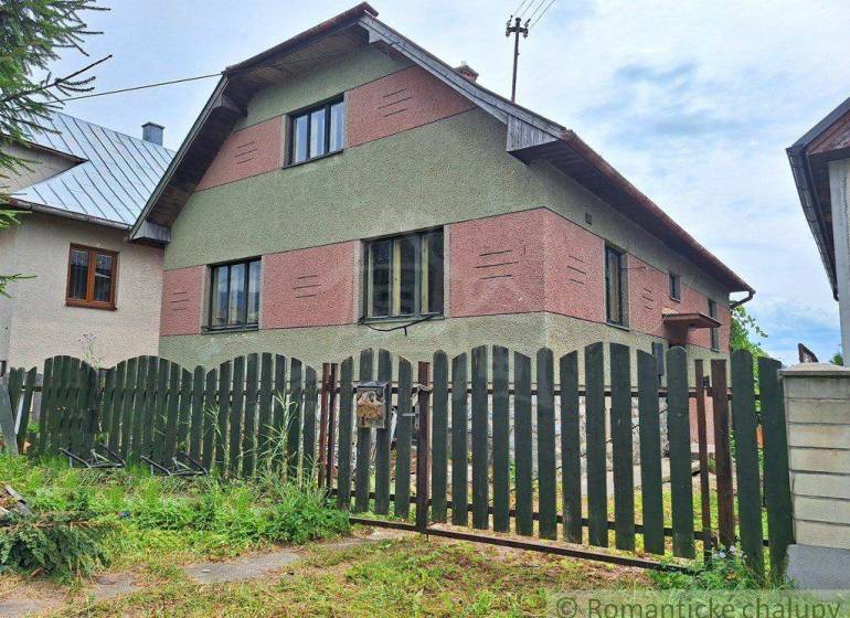 A family house with a grassy plot and a wooden fence, an electric pole is visible in the surroundings.