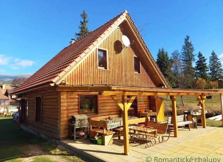 A cottage in nature with wooden decor, a large terrace, and a grill in the countryside.