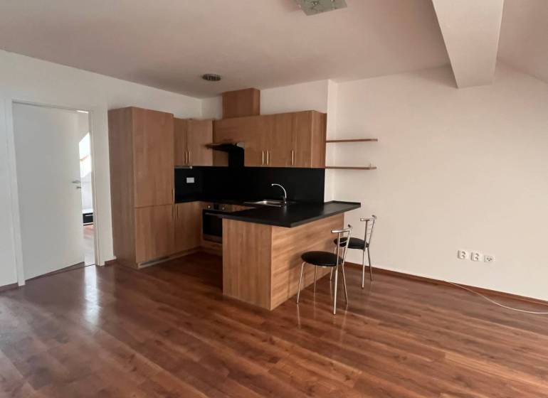 The kitchen in a 3-room apartment with wooden floors, a black countertop, and two chairs.