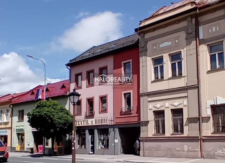 Commercial spaces in Brezno with colorful historical facades and parked cars.