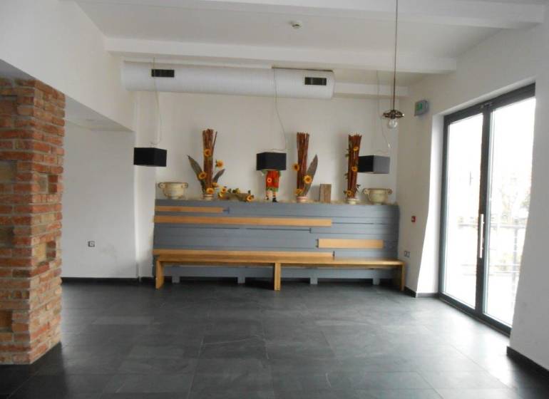 Interior of commercial spaces with decorative vases and a large window on the right side.