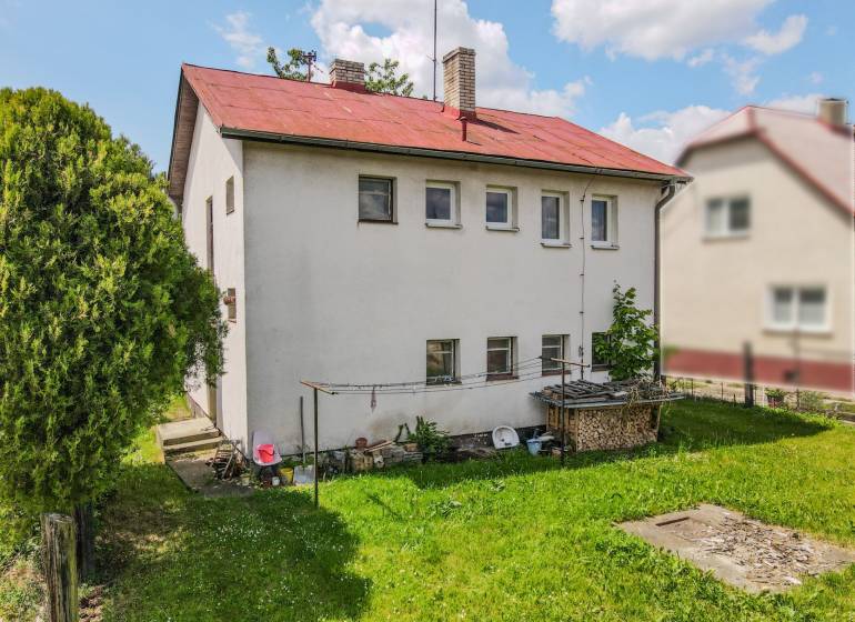 A family house in Pruské with a garden, white facade, and red roof.