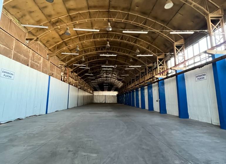 Interior of warehouses and halls with high ceilings, steel beams, and a row of lights.