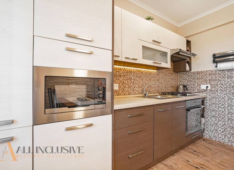 Modern kitchen in a 2-room apartment with wooden flooring and built-in appliances.