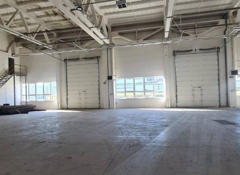 Industrial interior with a large open space and garage doors, suitable for warehouses and halls.
