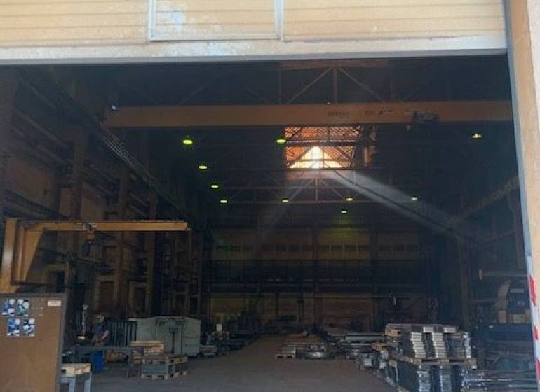 Interior of warehouses and halls with high ceilings, pallets, and lighting.