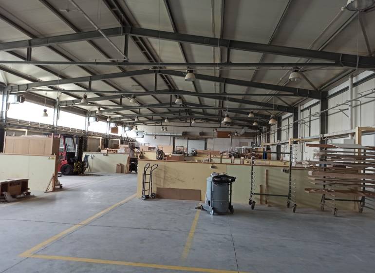 Spacious interior of warehouses and halls with shelves, equipment, and a material cart.