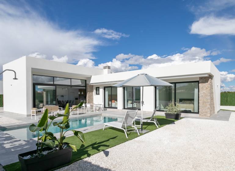 The villa in Calasparra has a swimming pool, a terrace with loungers, and a parasol under the blue sky.