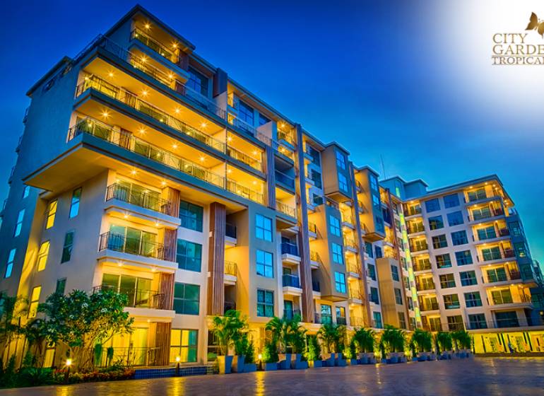 Apartment construction in Pattaya in the evening, illuminated modern apartment complex, logo 1BCR, verified member.